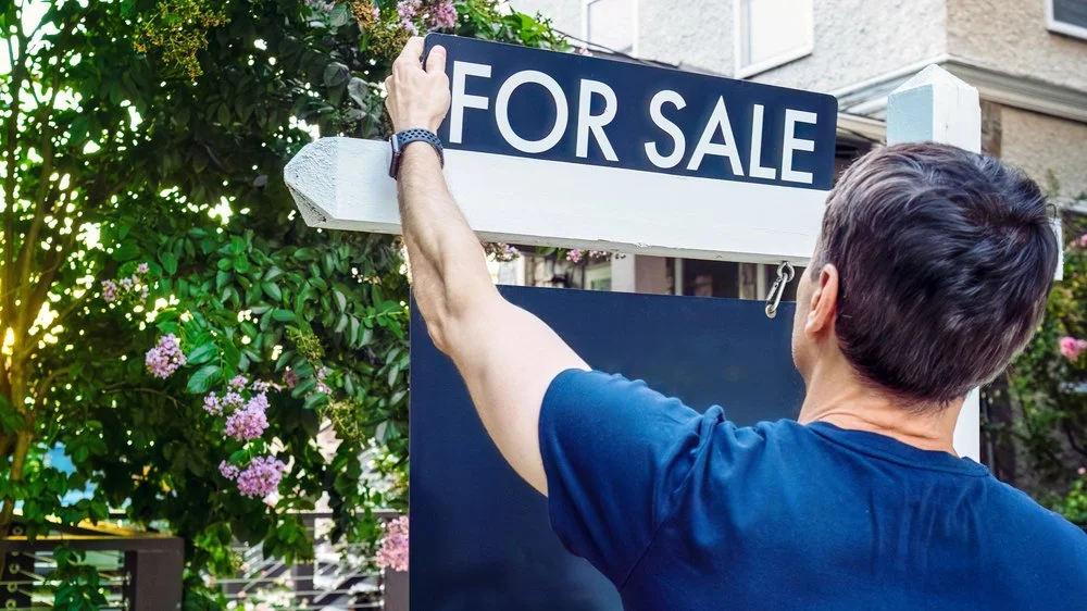 Real Estate Agent Adjusts For Sale Sign in Front Yard